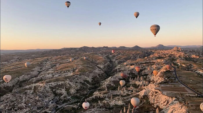 Hot air balloons floating over rocky landscape during sunrise