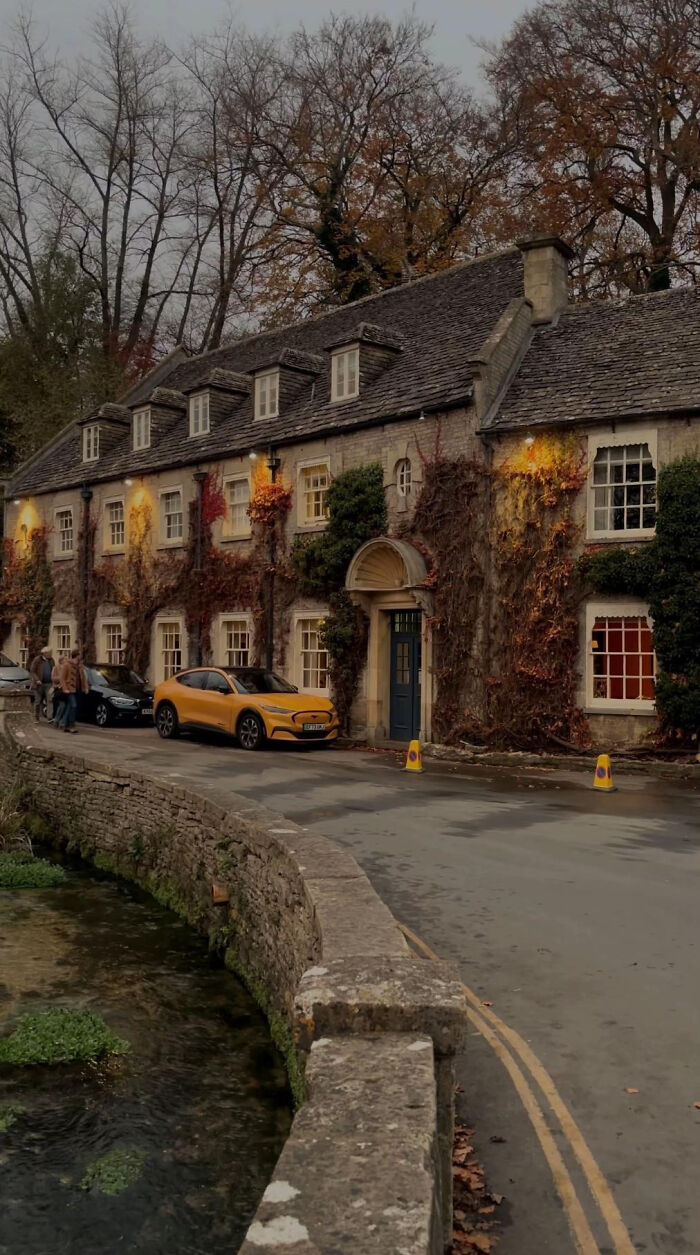Aesthetic vintage stone house covered with autumn ivy along a quiet riverside street
