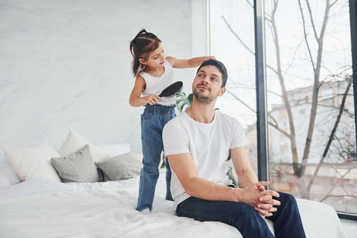 A little girl combs her father's hair as part of a post-intimacy scene being staged.