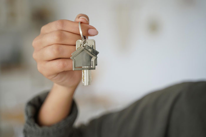 A hand holding house keys, symbolizing a creepy friend's attempt to steal a hubby.