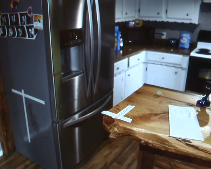 A kitchen with a refrigerator and wooden table, showing gruesome details related to Taylor Parker.
