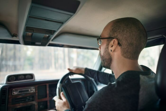 A man driving a car, looking out the window, experiencing something creepy.