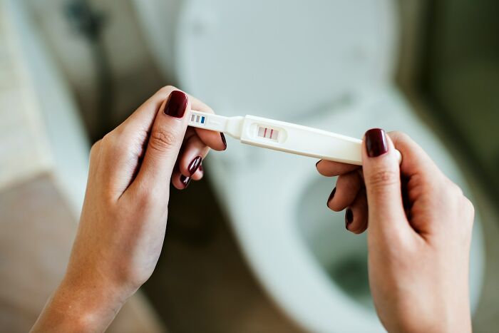 Hands holding a positive pregnancy test, a significant life event that can impact divorced people.