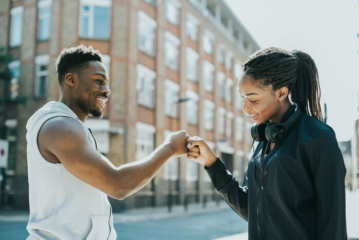Smiling couple fist bumping outdoors in city