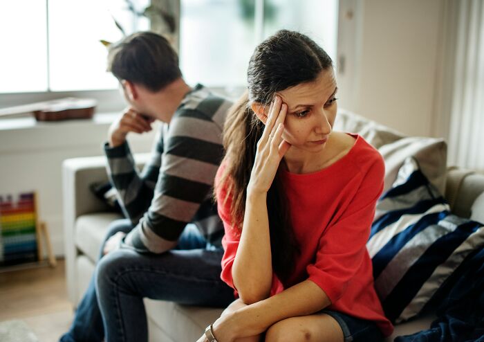 Upset woman and man sitting on couch looking away after a fight