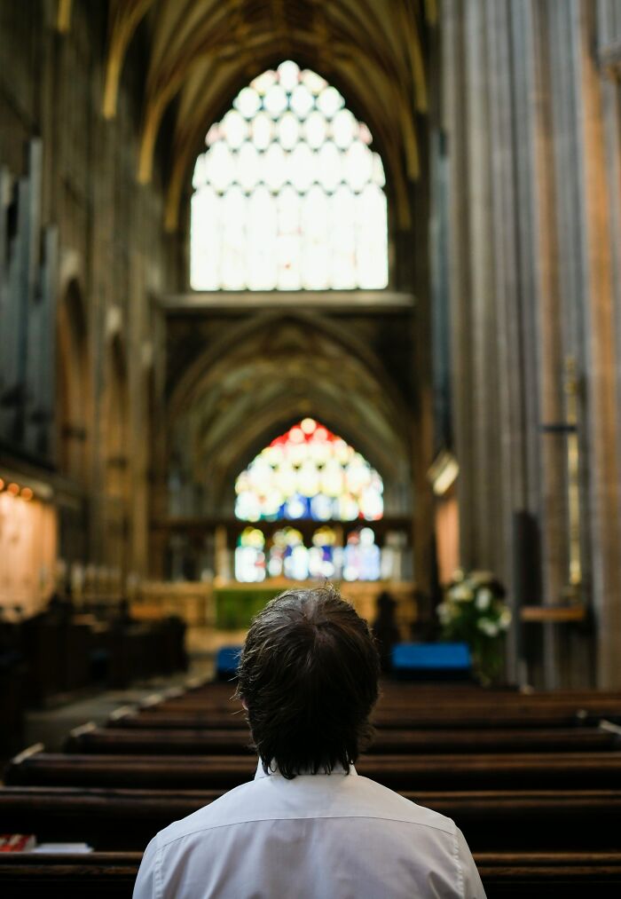 A man sitting alone in a church, reflecting on the surprising double lives and secrets people keep.