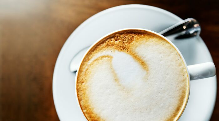 Top view of cappuccino coffee with spoon on saucer