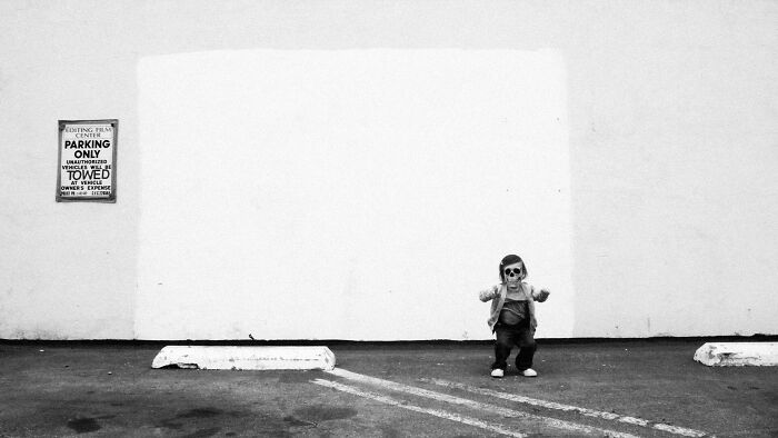 Black and white photo of child in eerie skull mask in lot