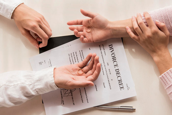 Hands holding wedding rings over a divorce decree, symbolizing the ex-stepmom's past and the bride's current wedding.