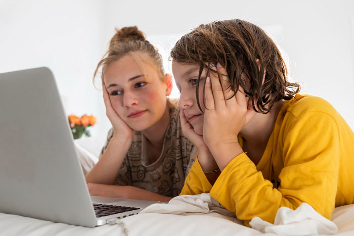 Two girls looking at a laptop, illustrating the bride's past family issues before her wedding.