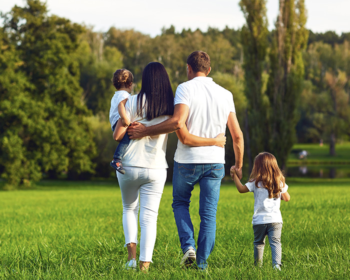 A family with two kids walks in a field; dads and wives often share experiences after kids.