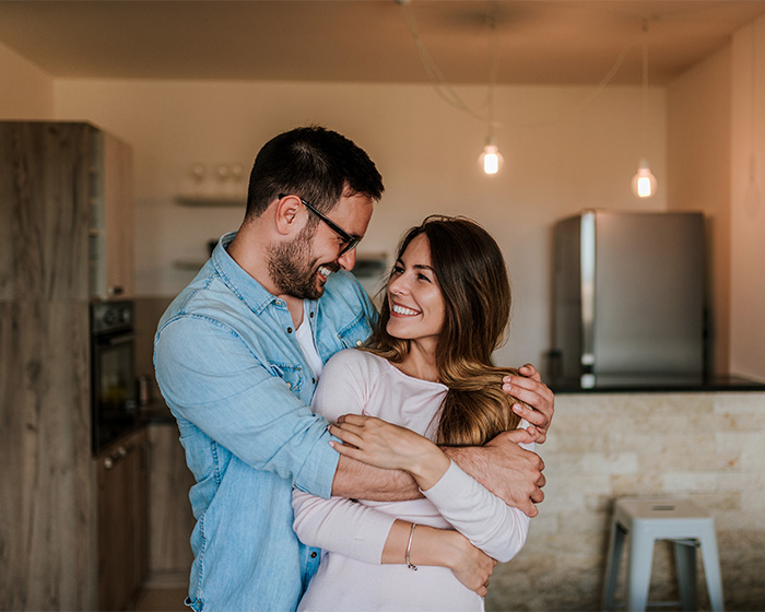 A happy couple embracing, a psychologist asked dads what their wives stopped doing after kids, responses got heavy.