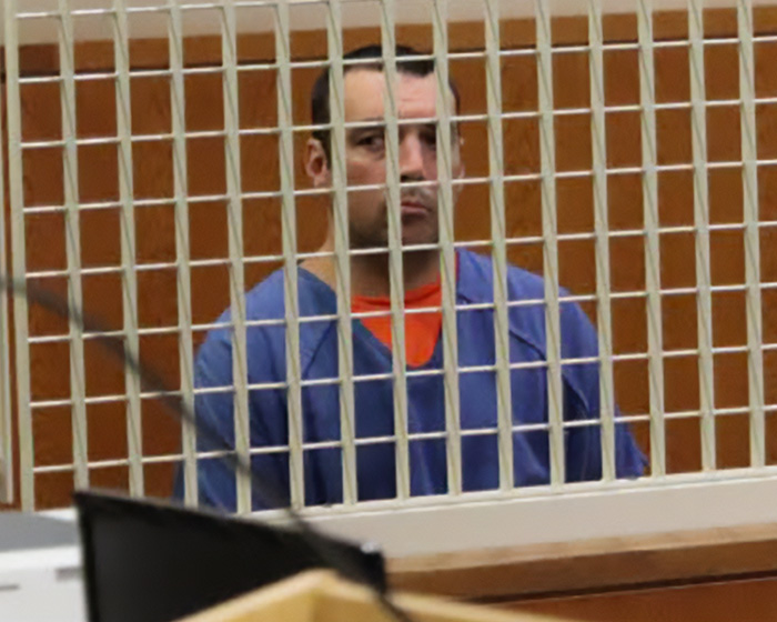 A man in a blue jumpsuit behind a cage, related to a disturbing relationship with daughter and dad's sentence.