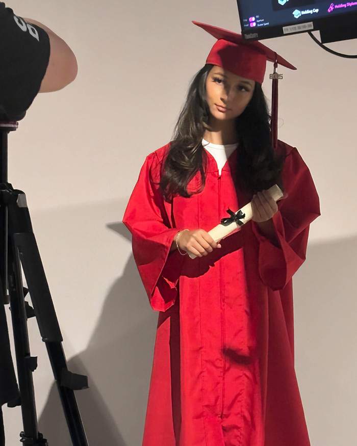 The daughter in a disturbing relationship with her dad wears a graduation cap and gown, holding a diploma.