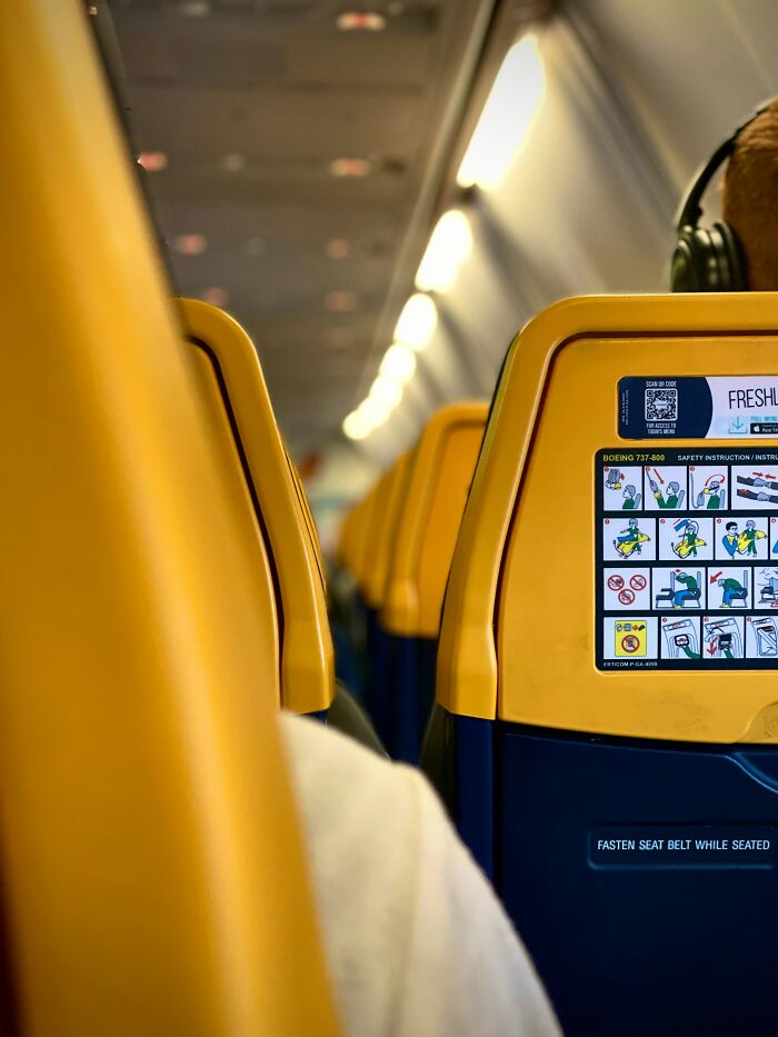 Airplane seats with safety instruction card and passenger wearing headphones
