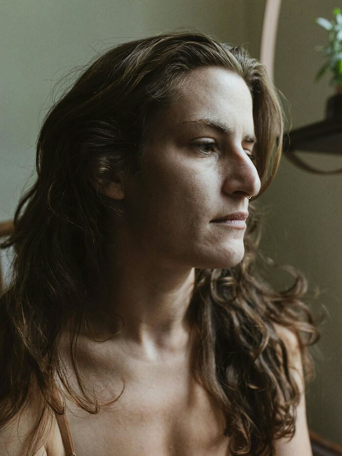 A pensive woman with long hair, looking away, reflecting on the complexities of double lives.