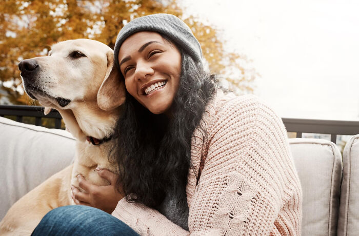 A young woman happily hugging a golden retriever, showing positive human behavior and truths about happiness.
