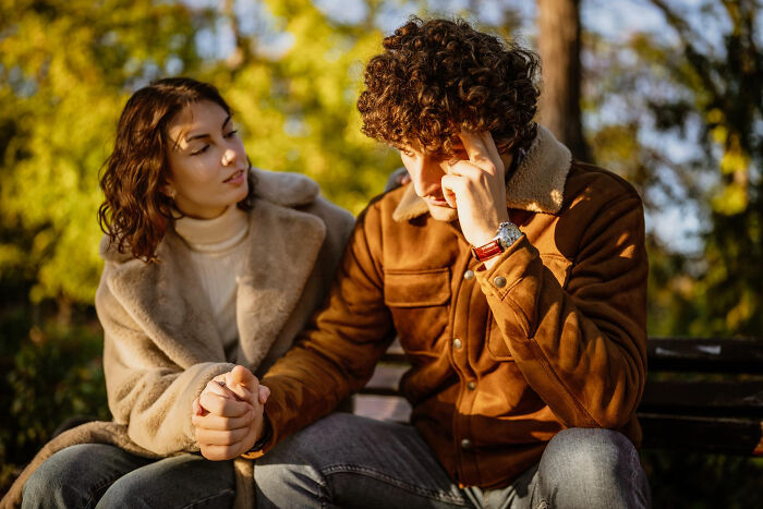 A supportive woman holding a distressed man's hand, illustrating complex human behavior.