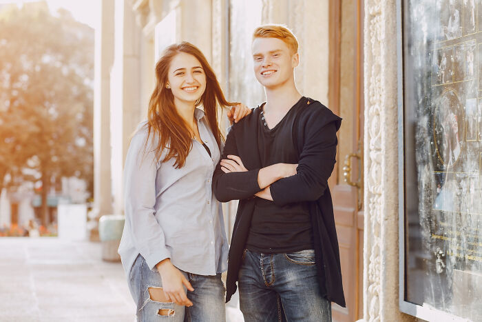 A happy young couple smiling at the camera, exemplifying positive human behavior.