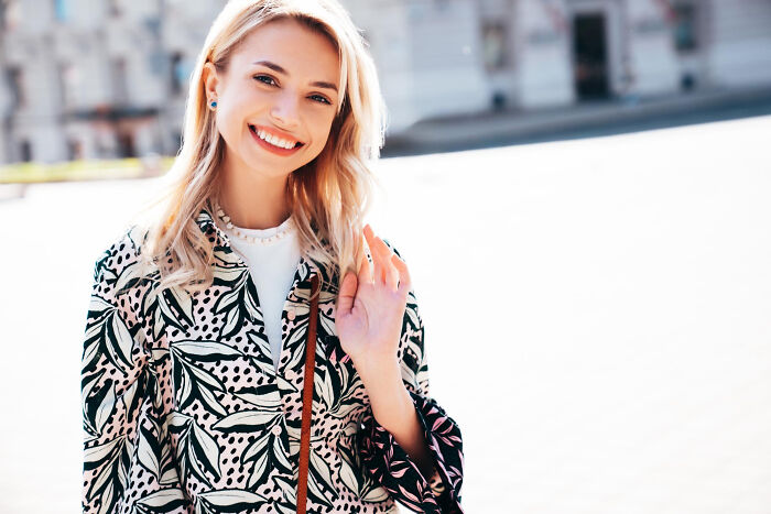 A smiling woman in a stylish outfit, representing an aspect of human behavior and appearance.