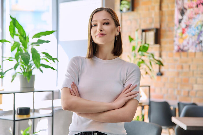A confident young woman with crossed arms, representing resilient human behavior.