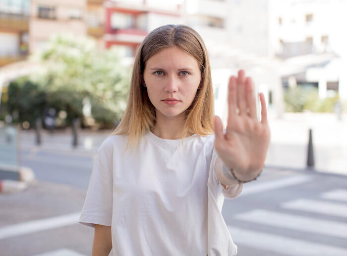 A woman with an outstretched hand, showing a stop gesture, illustrating assertive human behavior.