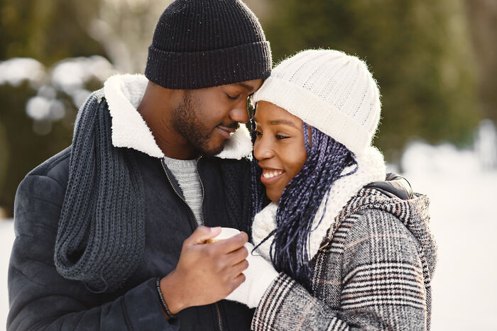 A happy couple embracing in the snow, representing human behavior related to love and connection.