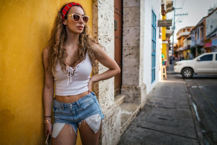 Young woman posing outdoors wearing trendy summer clothes and sunglasses