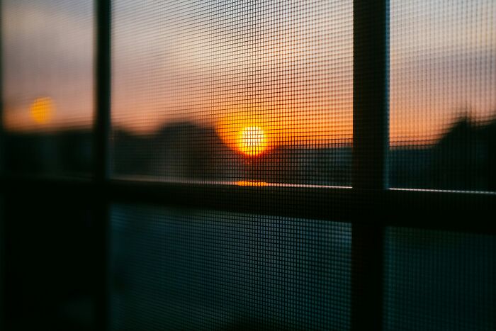 Sunset viewed through window screen with blurred background