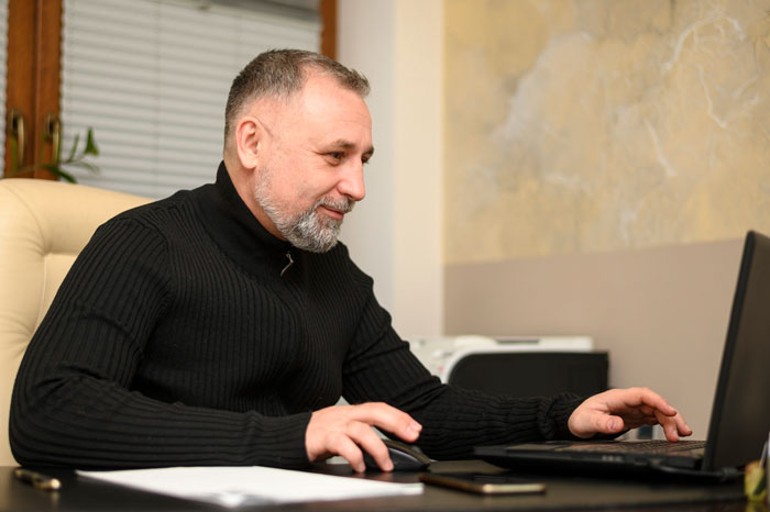 Man researching prenup and fiancé's dating history on laptop Man researching prenup and fiancé's dating history on laptop
