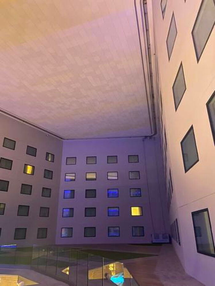An eerie, enclosed courtyard of a building with glowing windows at night, creating a haunting liminal space.