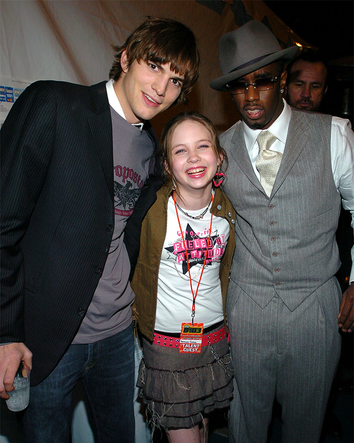 Ashton Kutcher, Lilo & Stitch actress, and Diddy posing together at an event.