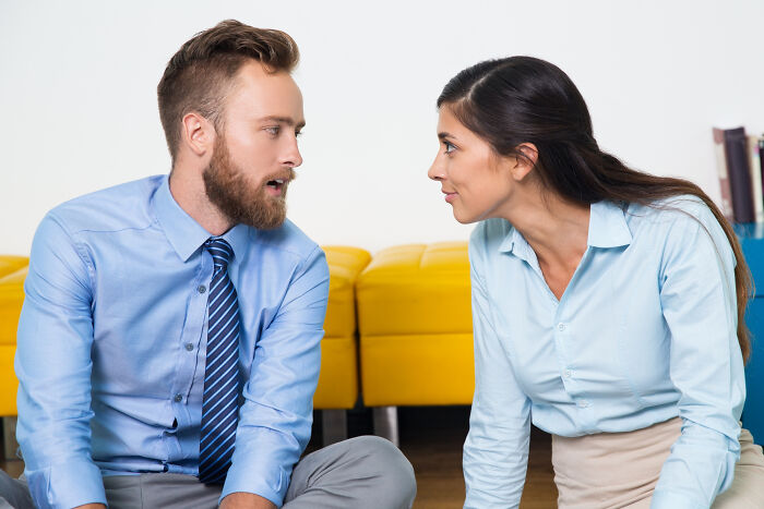 Man and woman in business attire having conversation seated on floor