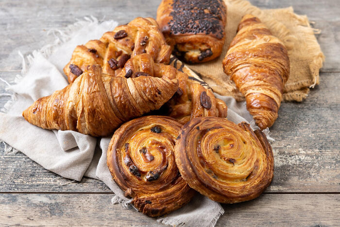 Assorted freshly baked croissants and pastries on rustic wooden table