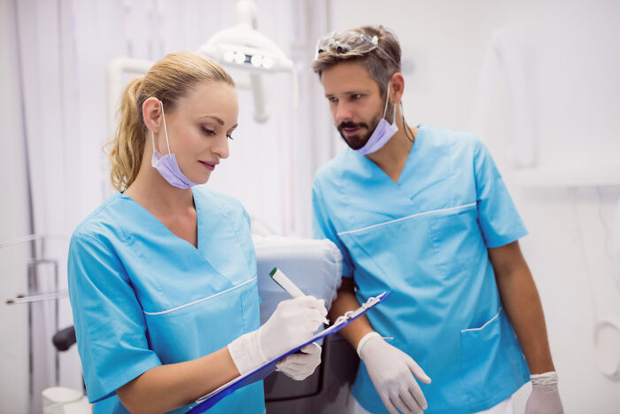 Two medical professionals discussing notes showing knowledge of specific facts