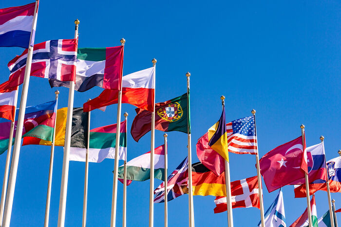 Collection of international flags flying against clear blue sky