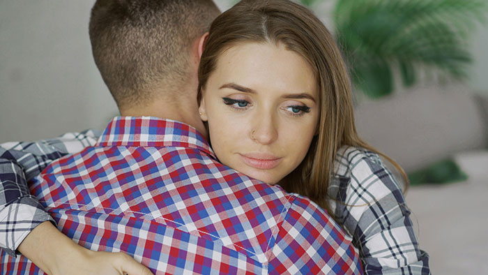 Woman unhappy while hugging her partner, noticing red flags