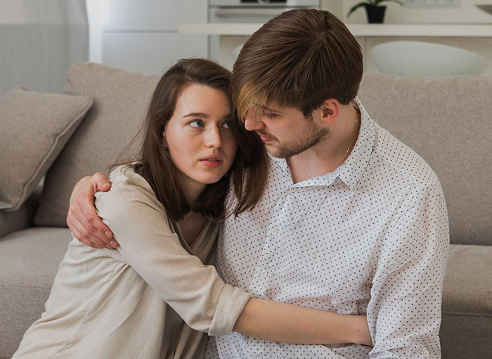 Couple embracing on sofa in serious talk depicting relationship red flags