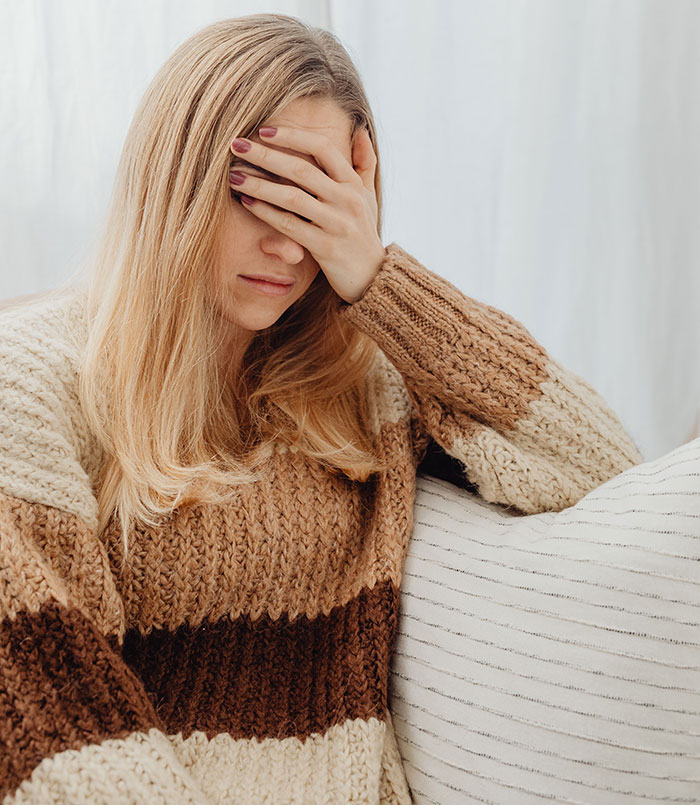 Upset woman covering face sitting on couch showing emotional relationship red flags