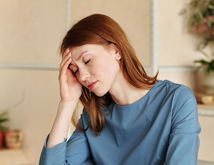 Red-haired woman holding head in frustration representing red flags missed after wedding