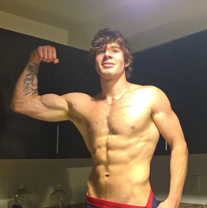 Shirtless muscular man flexing biceps in casual setting Shirtless muscular man flexing biceps in casual setting