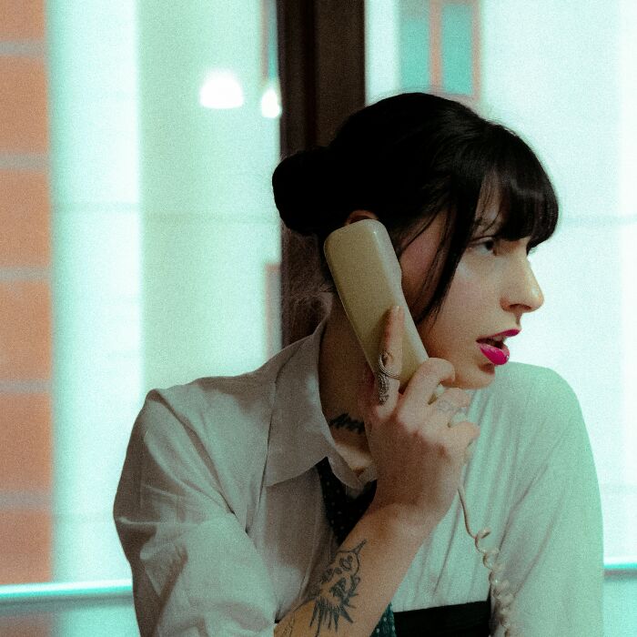 Woman with dark hair talking on vintage landline phone indoors