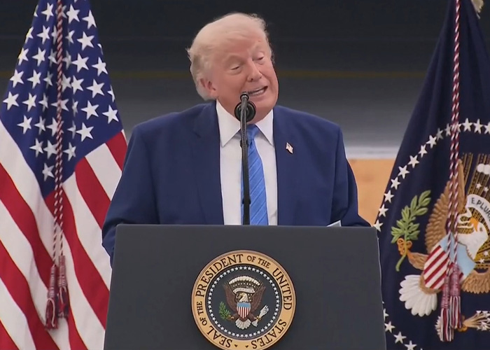 Donald Trump gaffe at a podium with American flags behind him.