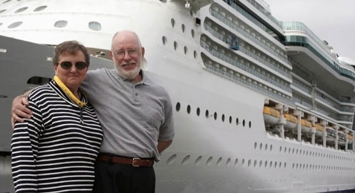 Older couple posing in front of cruise ship with positive stories keyword
