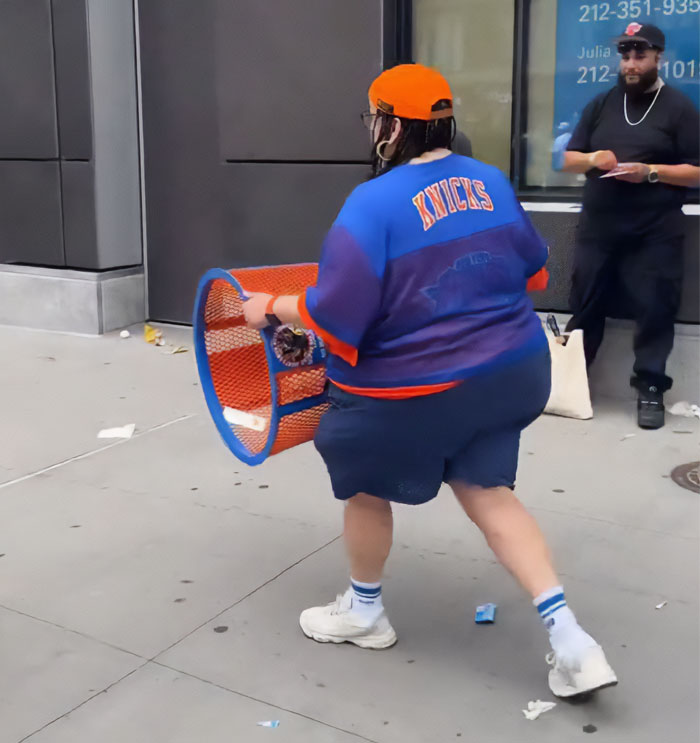 JPMorgan exec, in a Knicks shirt and orange hat, holding a stolen Knicks trashcan, caught in a viral video.