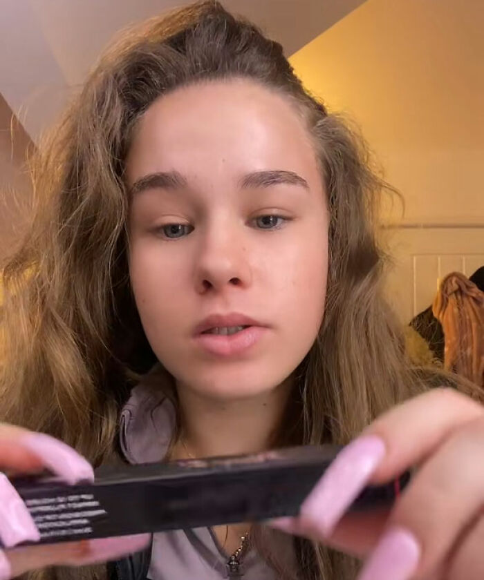 Influencer with long hair holding product in video close-up