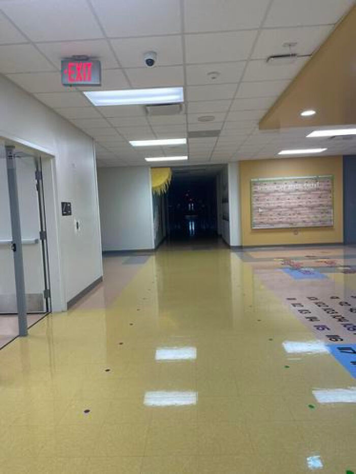 Deserted school hallway with brightly colored floors leading to darkness, a haunting liminal space.