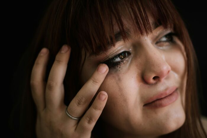 A crying woman wiping a tear from her eye, representing some useless facts.