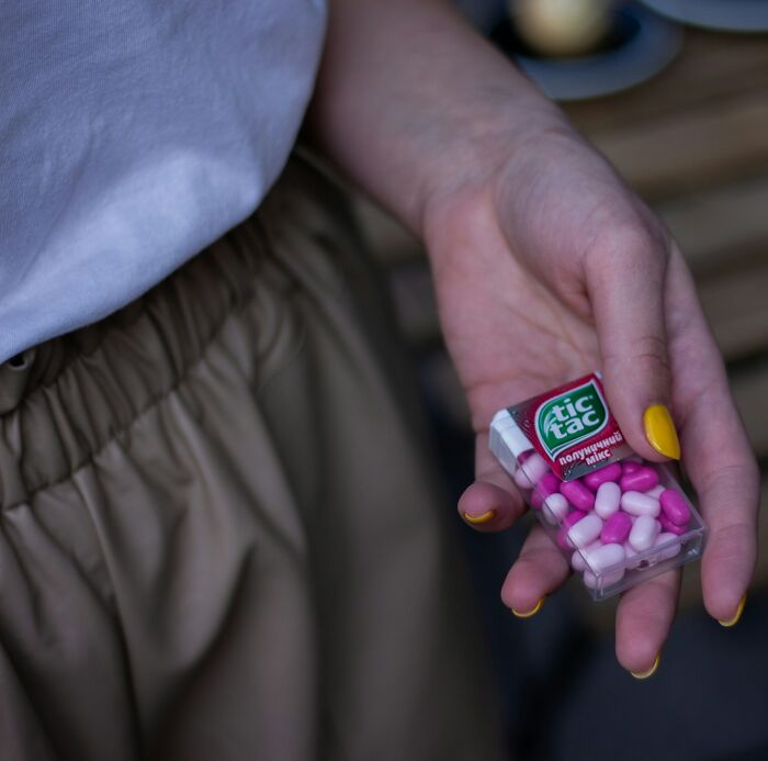 Hand holding pink and white Tic Tac mints food facts