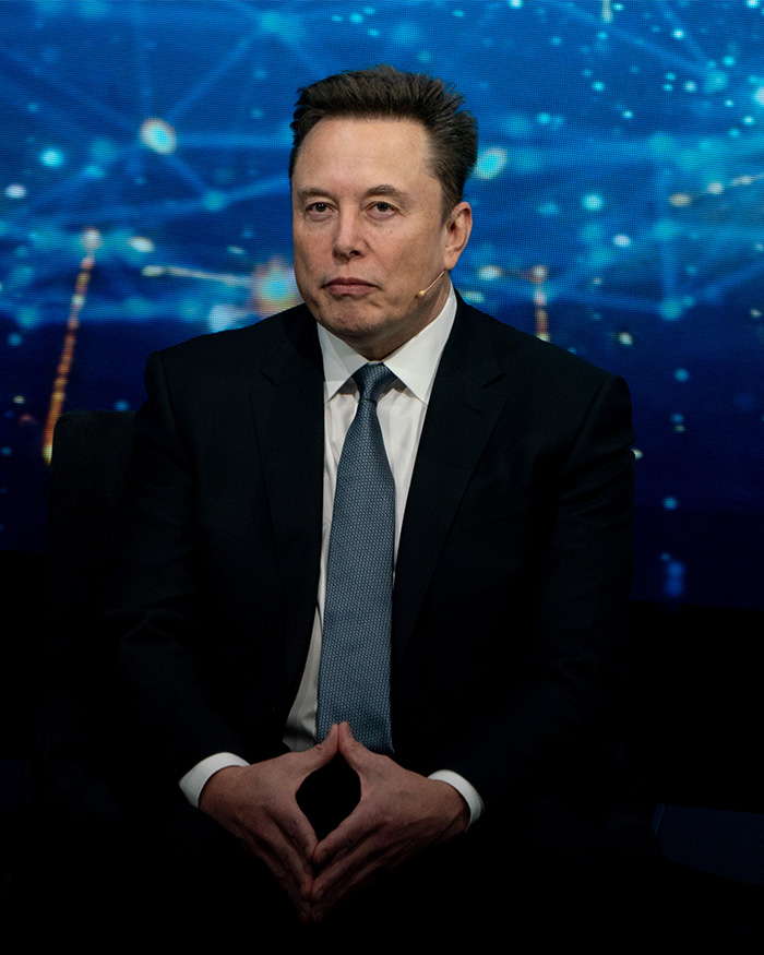 Elon Musk wearing suit and tie during a public speaking event Elon Musk wearing suit and tie during a public speaking event